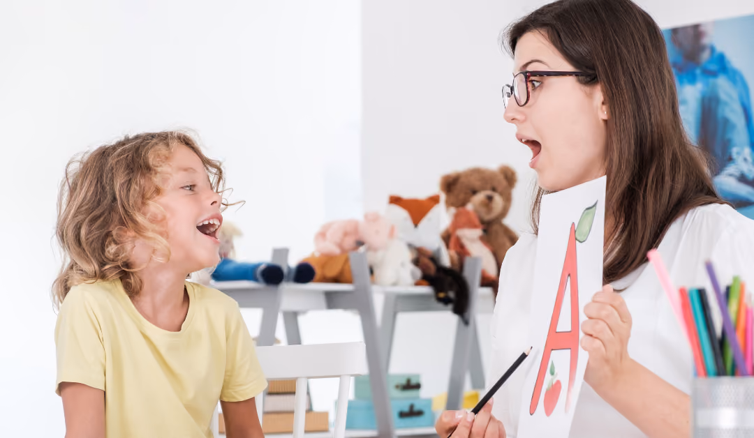 A speech therapist holding up a card with the letter A while a child copies the sound back to her.