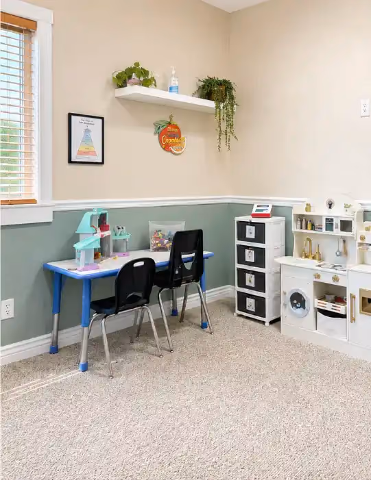 Child-sized play kitchen and table in the Rexburg clinic sensory play area.