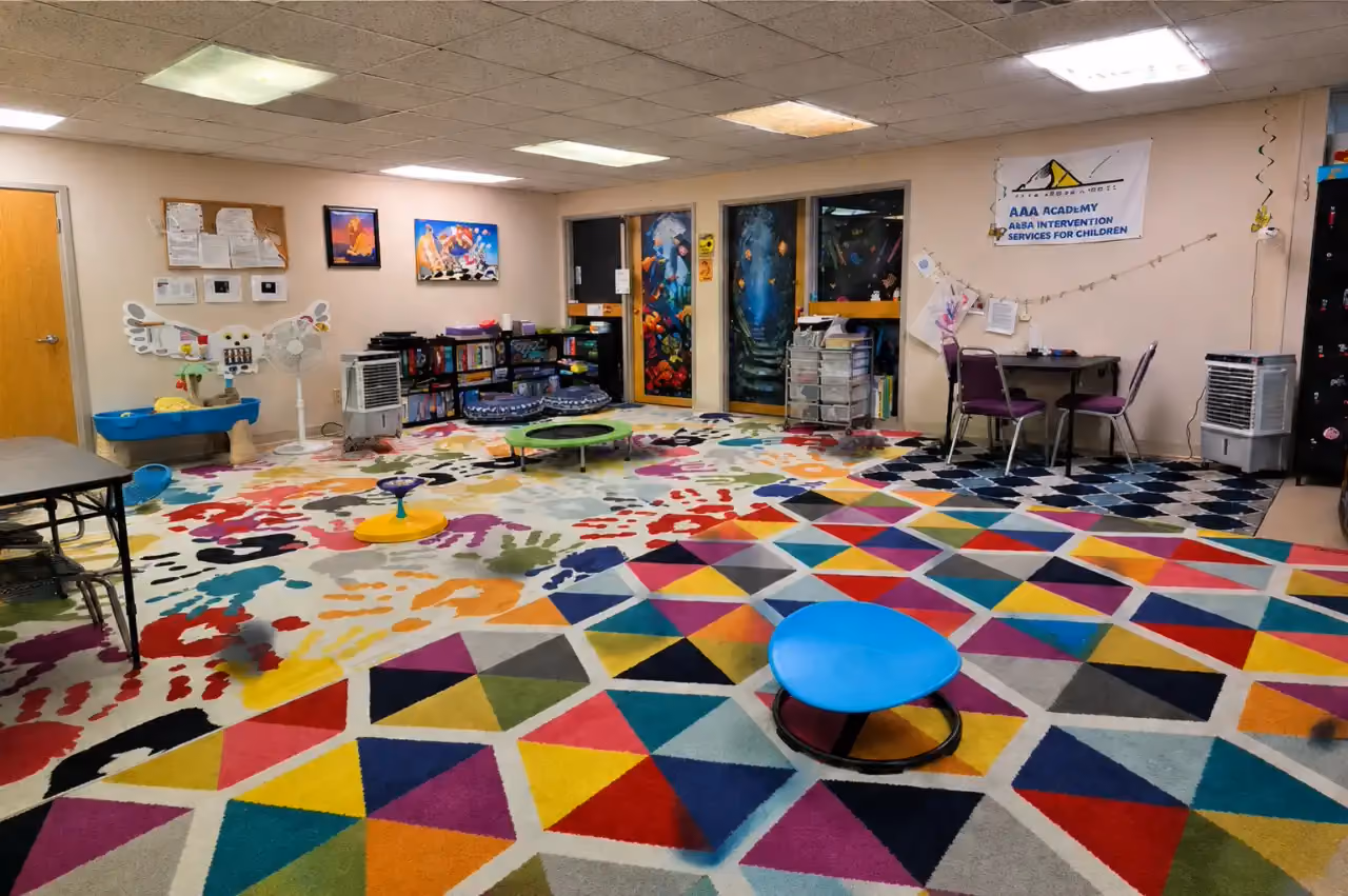 Therapy play room at the Rock Springs clinic with colorful rugs, toys, and child-sized tables.